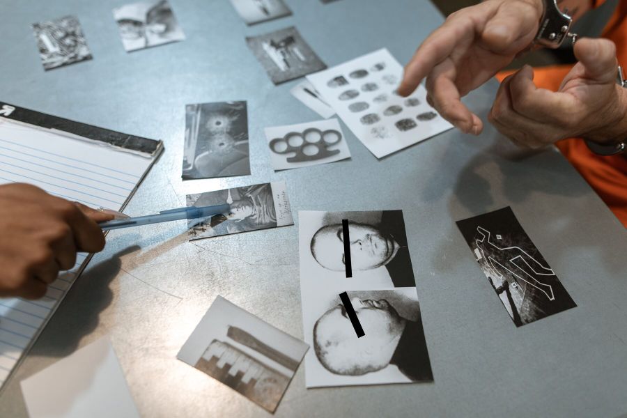 Investigative photographs, records and reference material laid out for review on a table.